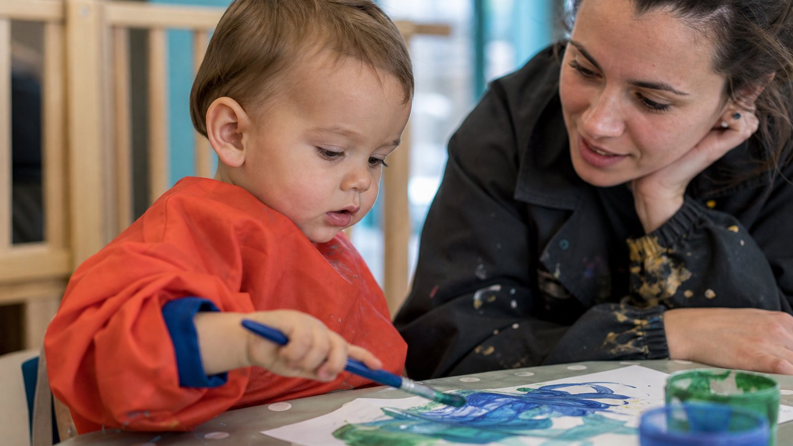 Enfant concentré sur une activité de peinture dans une salle de crèche
