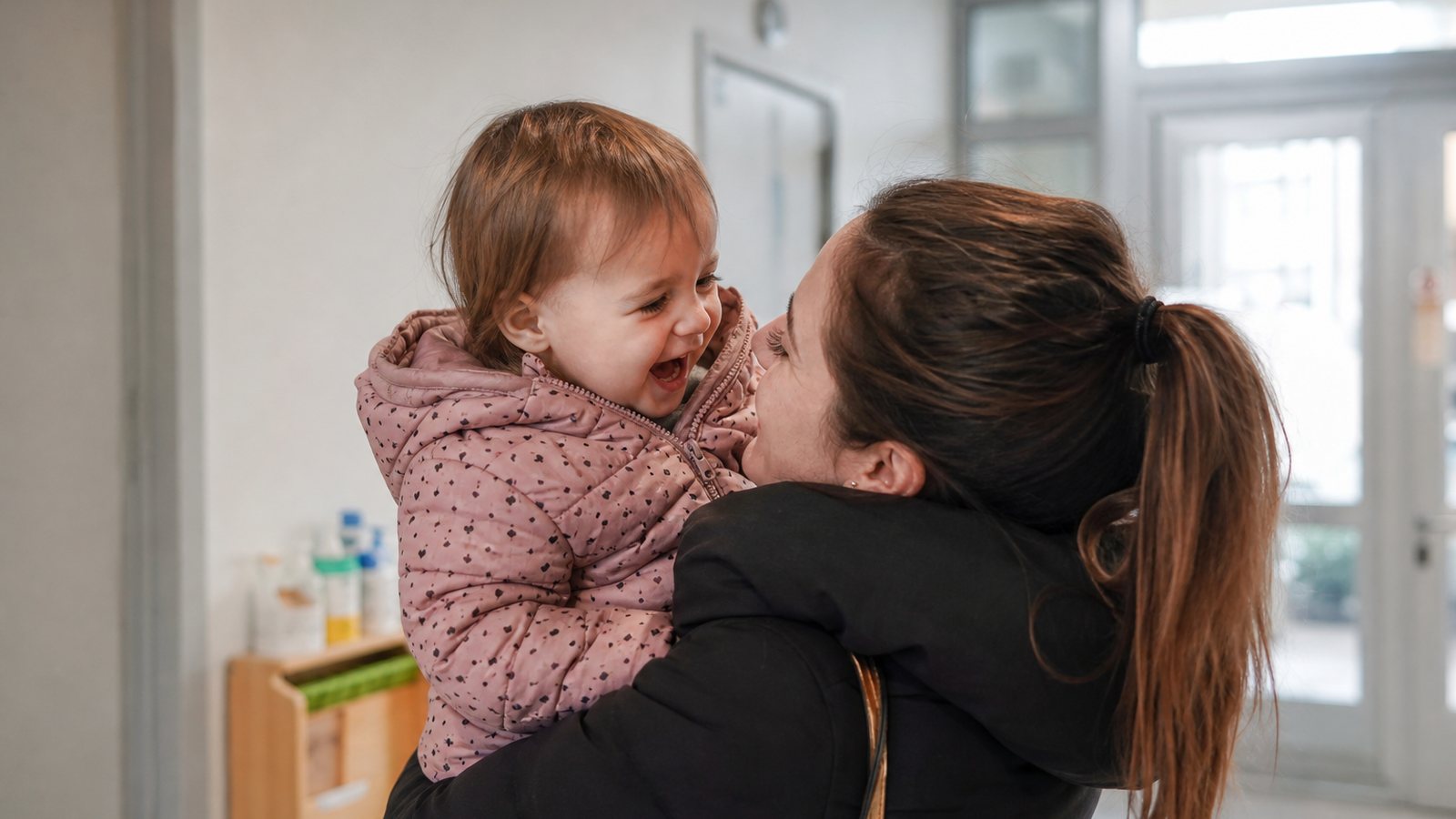 Parent rassuré retrouvant son enfant souriant à la sortie de la crèche