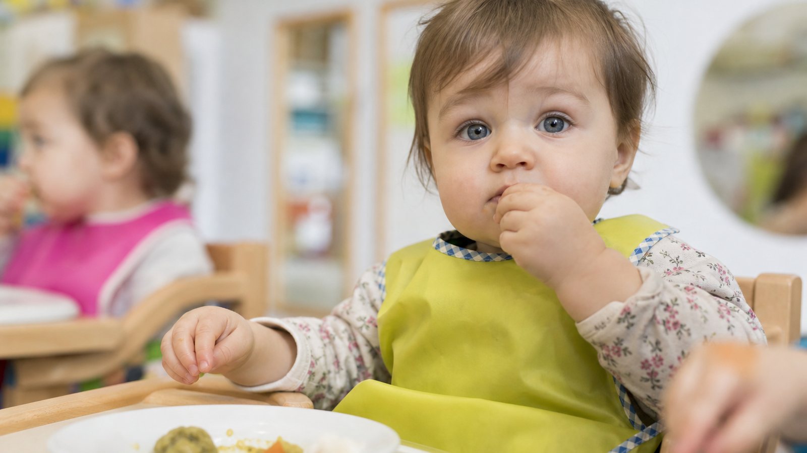 Tout-petit prenant son repas à une table adaptée dans une crèche